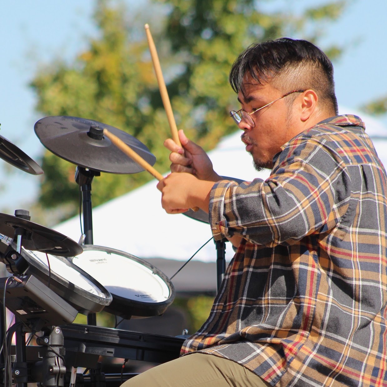 A musician playing an electronic drum kit during an outdoor festival performance.